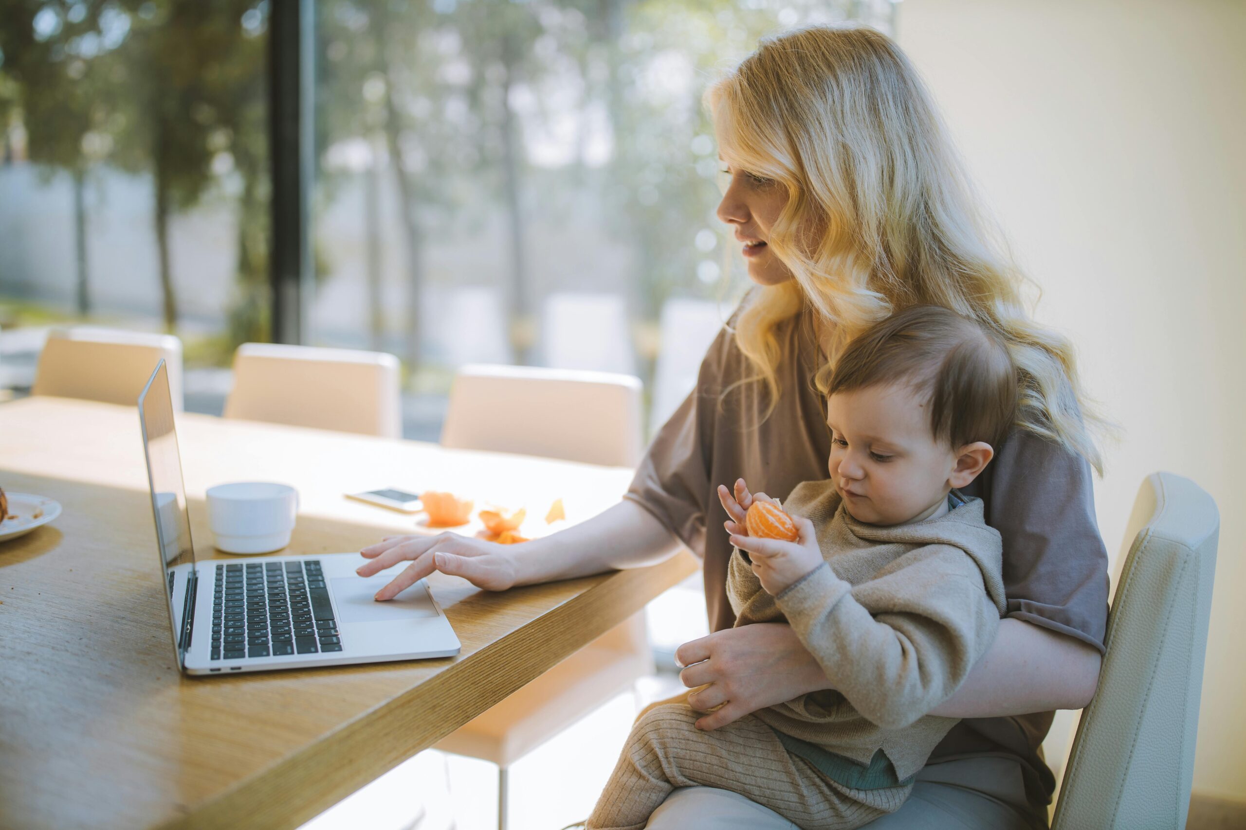 Woman sat with a baby on her lap, using a laptop